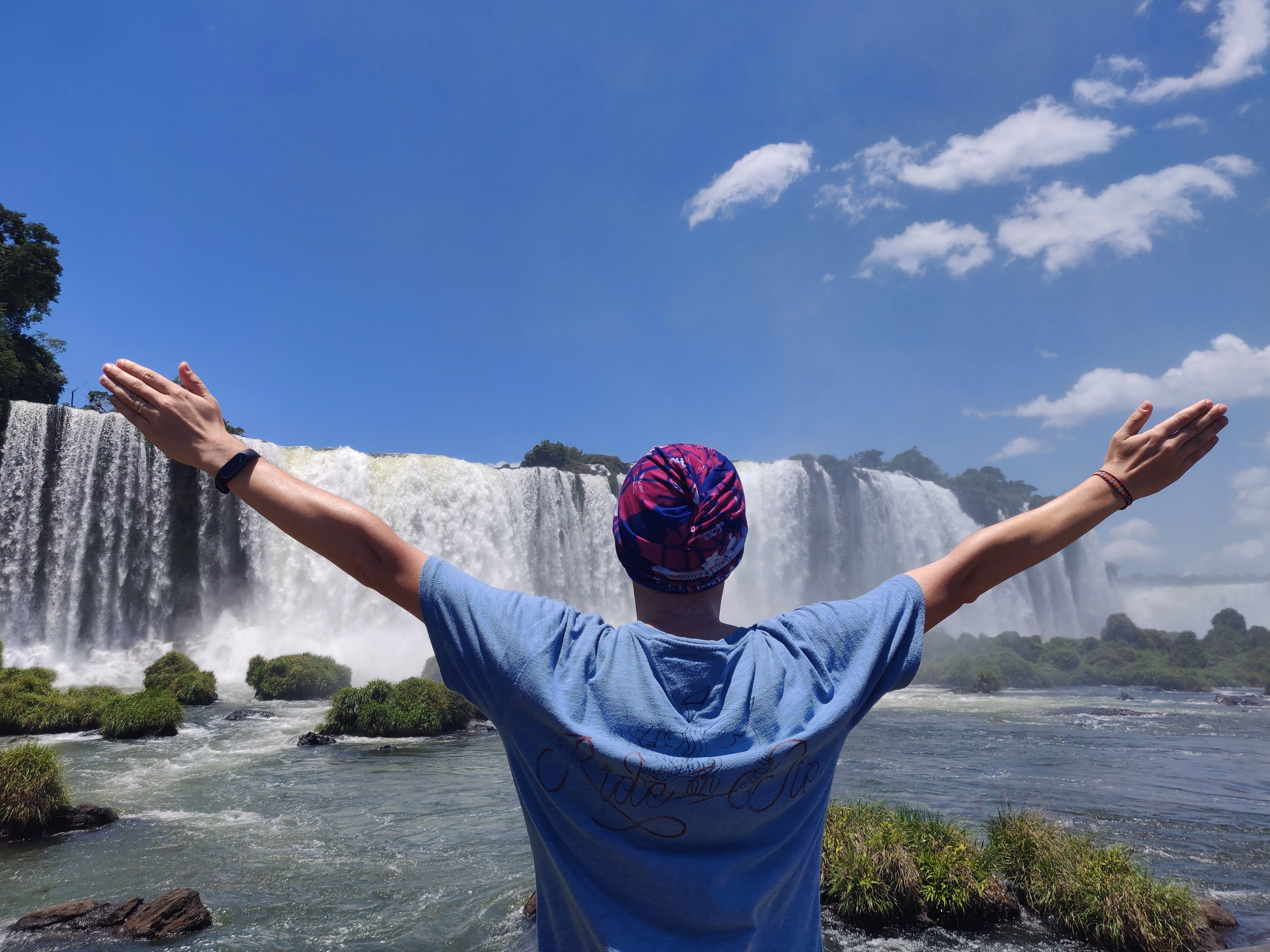 Alex with arms open facing Iguazu Falls
