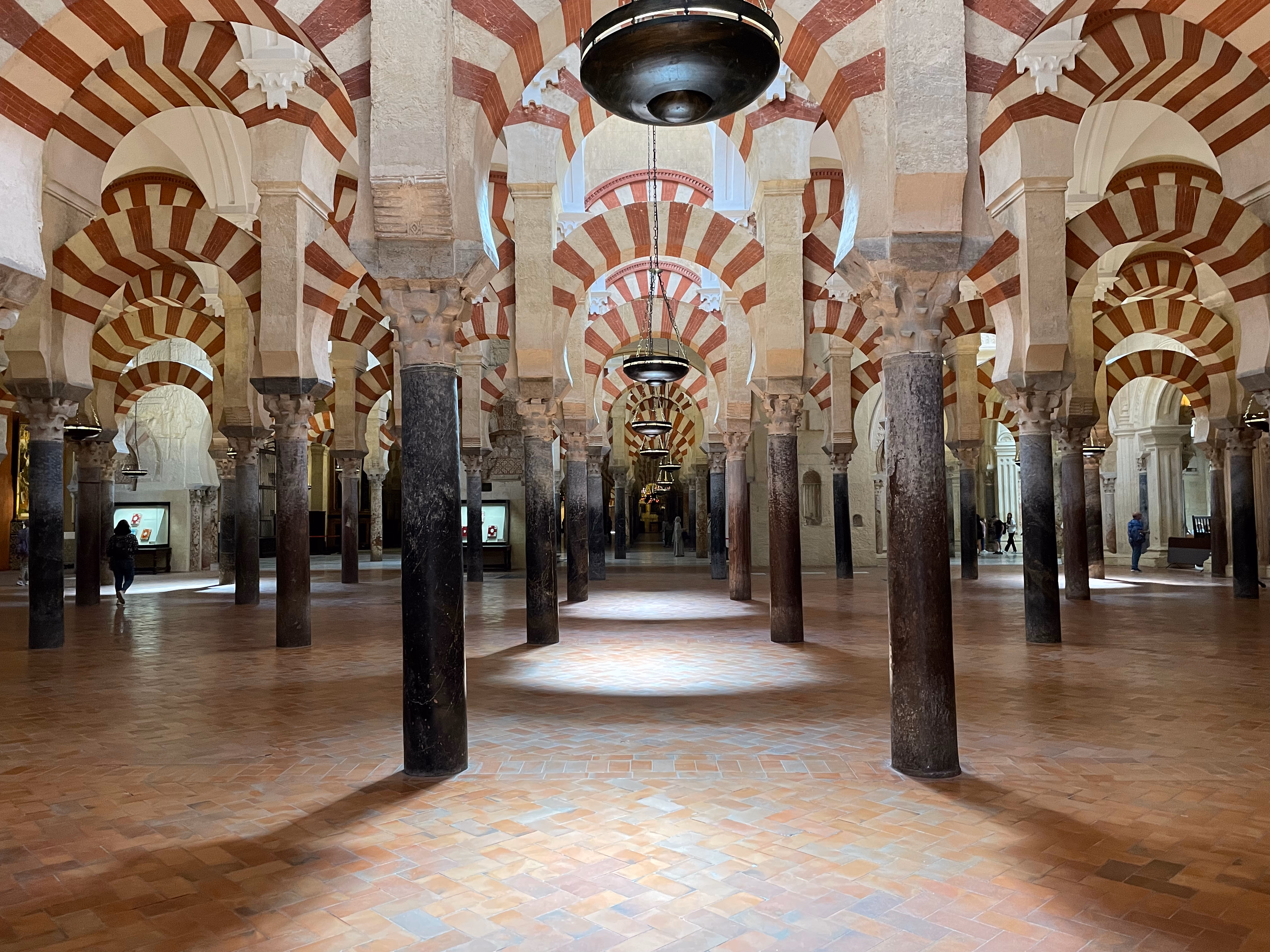 The forest of columns inside the Mezquita — tiered red-and-white striped arches stretching into the dim interior.