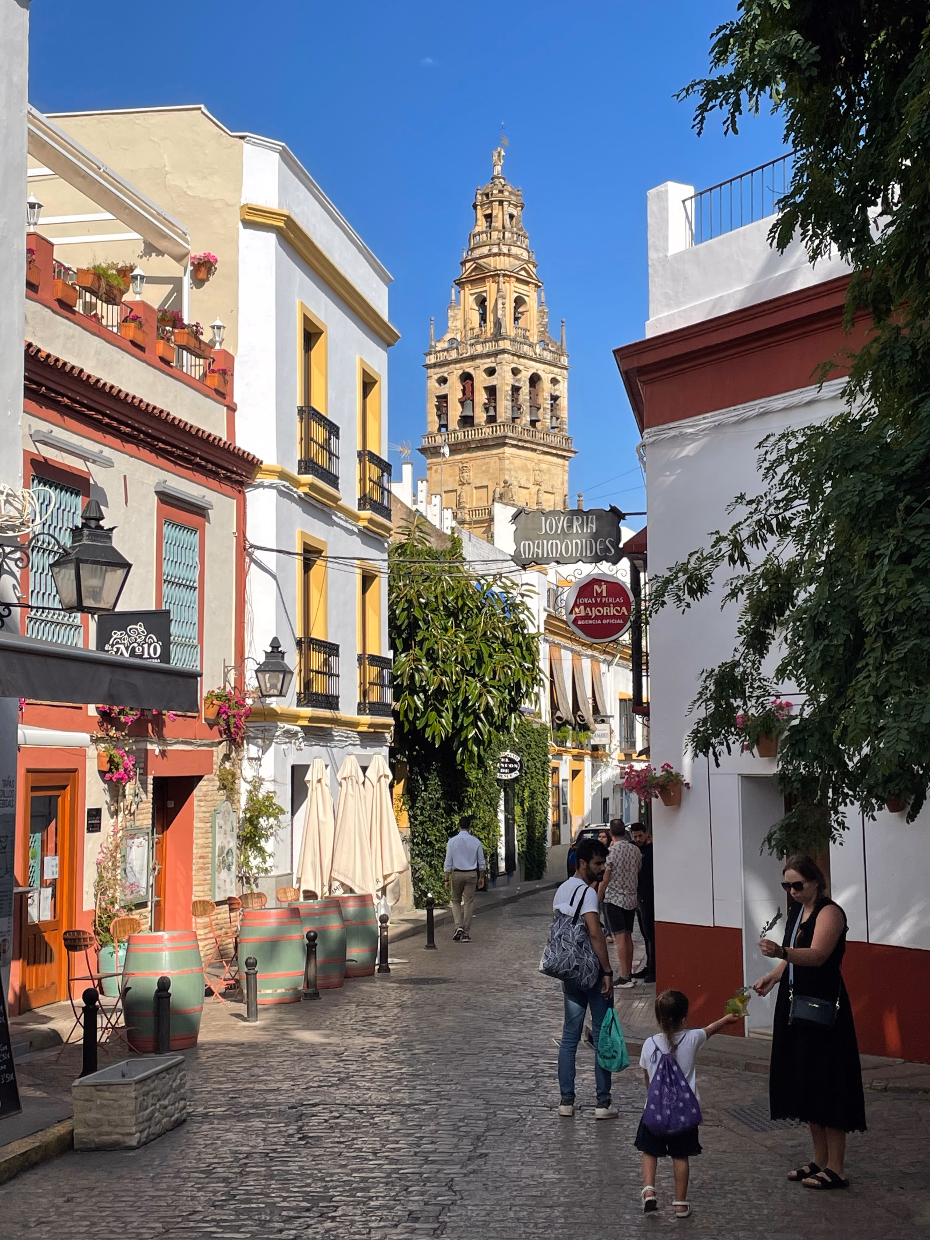 A cobbled lane in the Jewish quarter, the Mezquita bell tower framed at the end of the street.