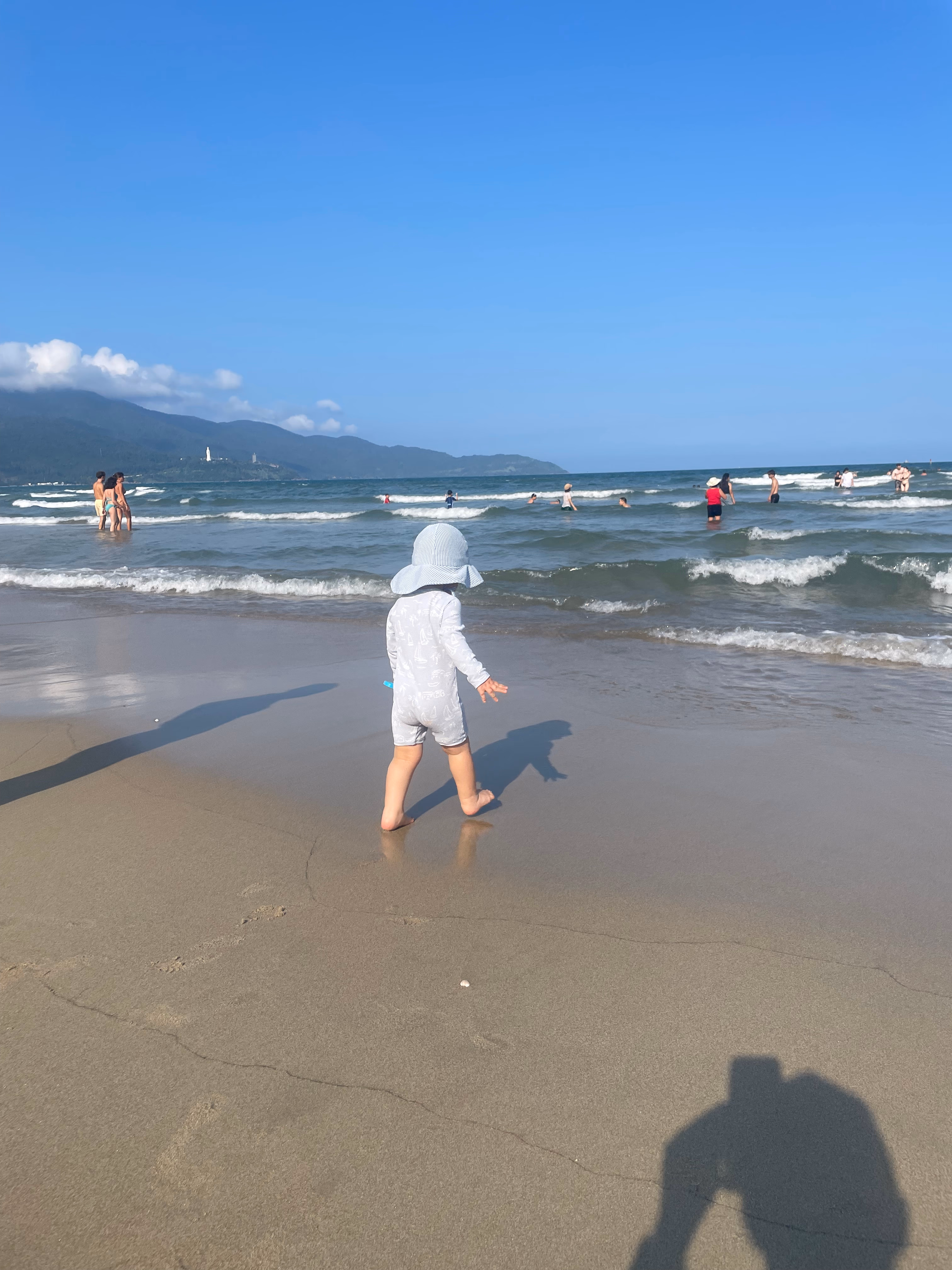Toddler walking towards the water on Da Nang beach.