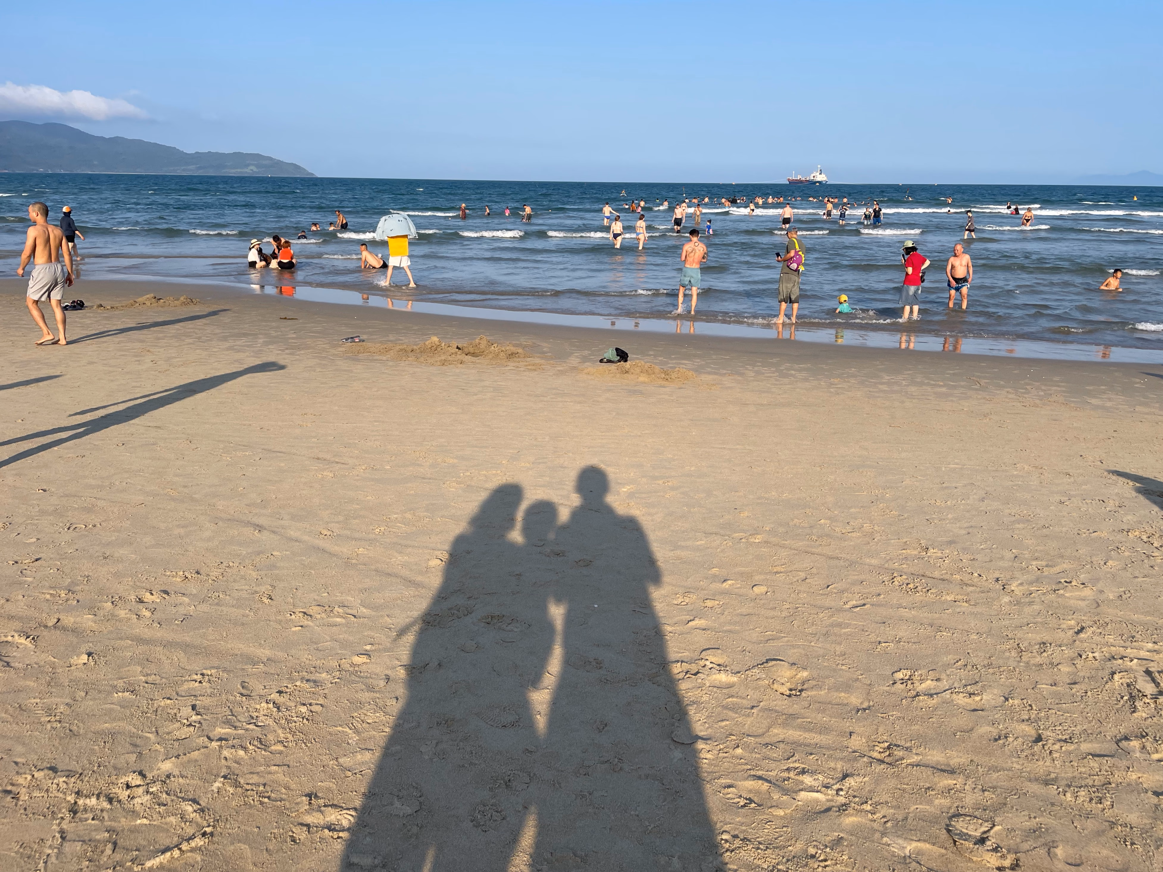 Family shadows on Da Nang beach at sunset.