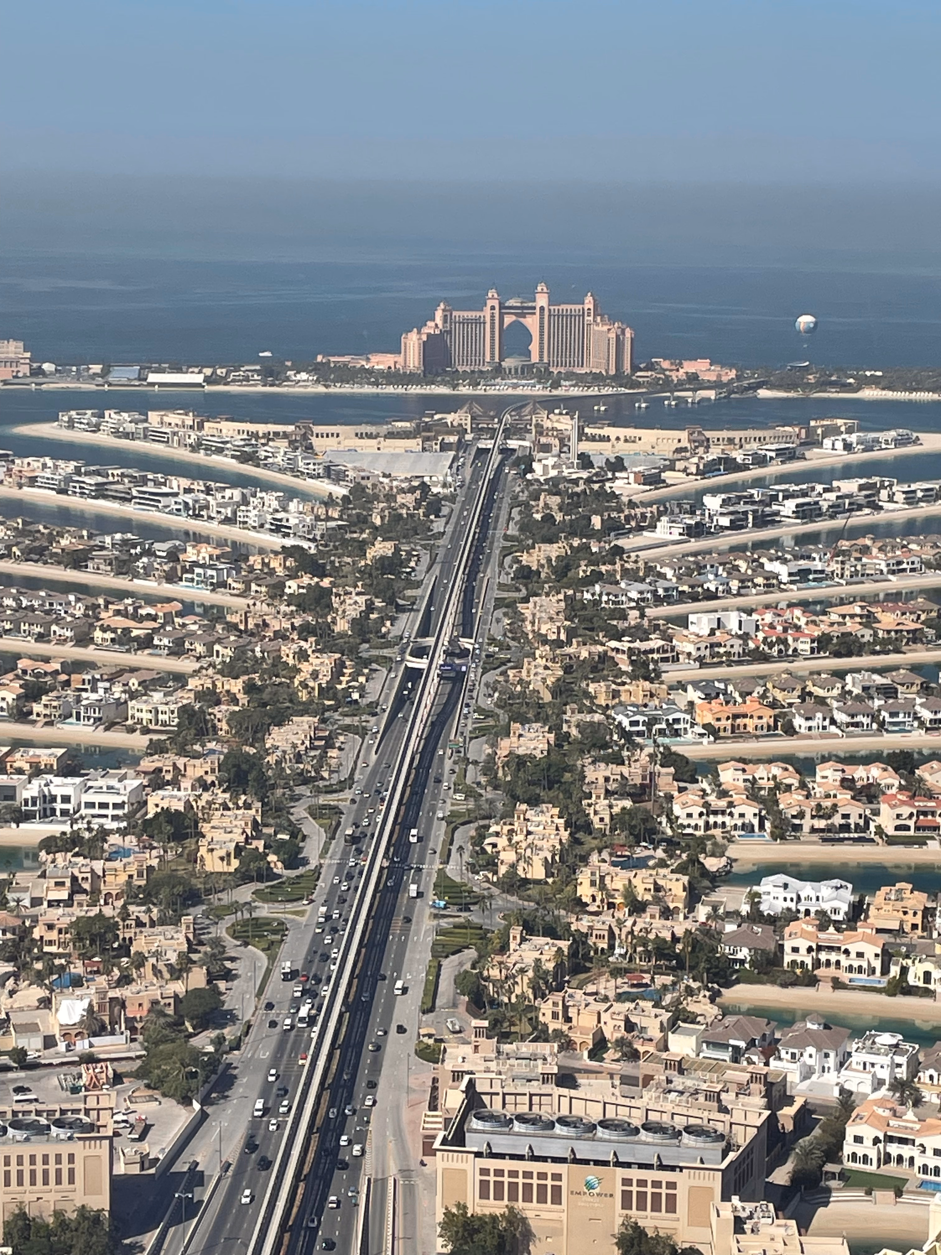 The Palm Jumeirah from above — a monorail spine lined with villas, fronds reaching into the Gulf toward Atlantis at the tip.