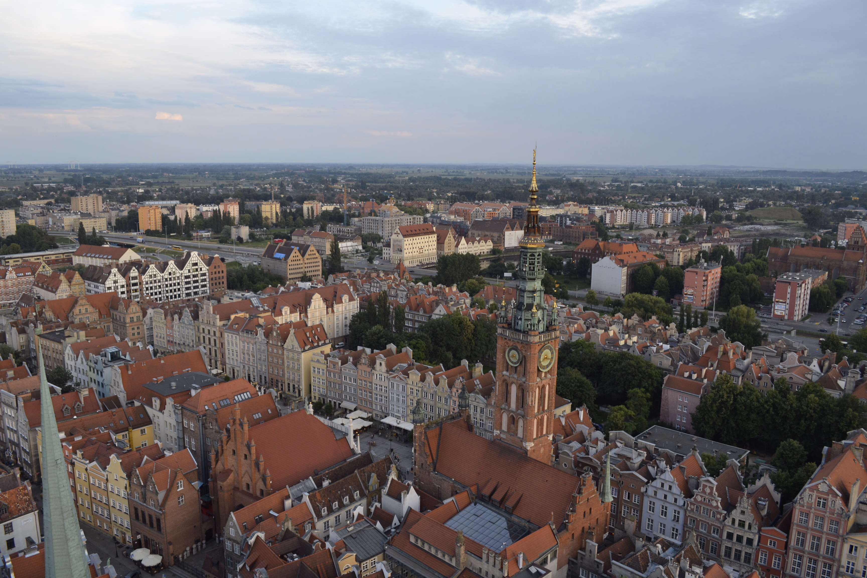 Gdańsk from above — the Main Town Hall's green spire rising above a sea of red-tiled roofs and pastel Hanseatic facades.