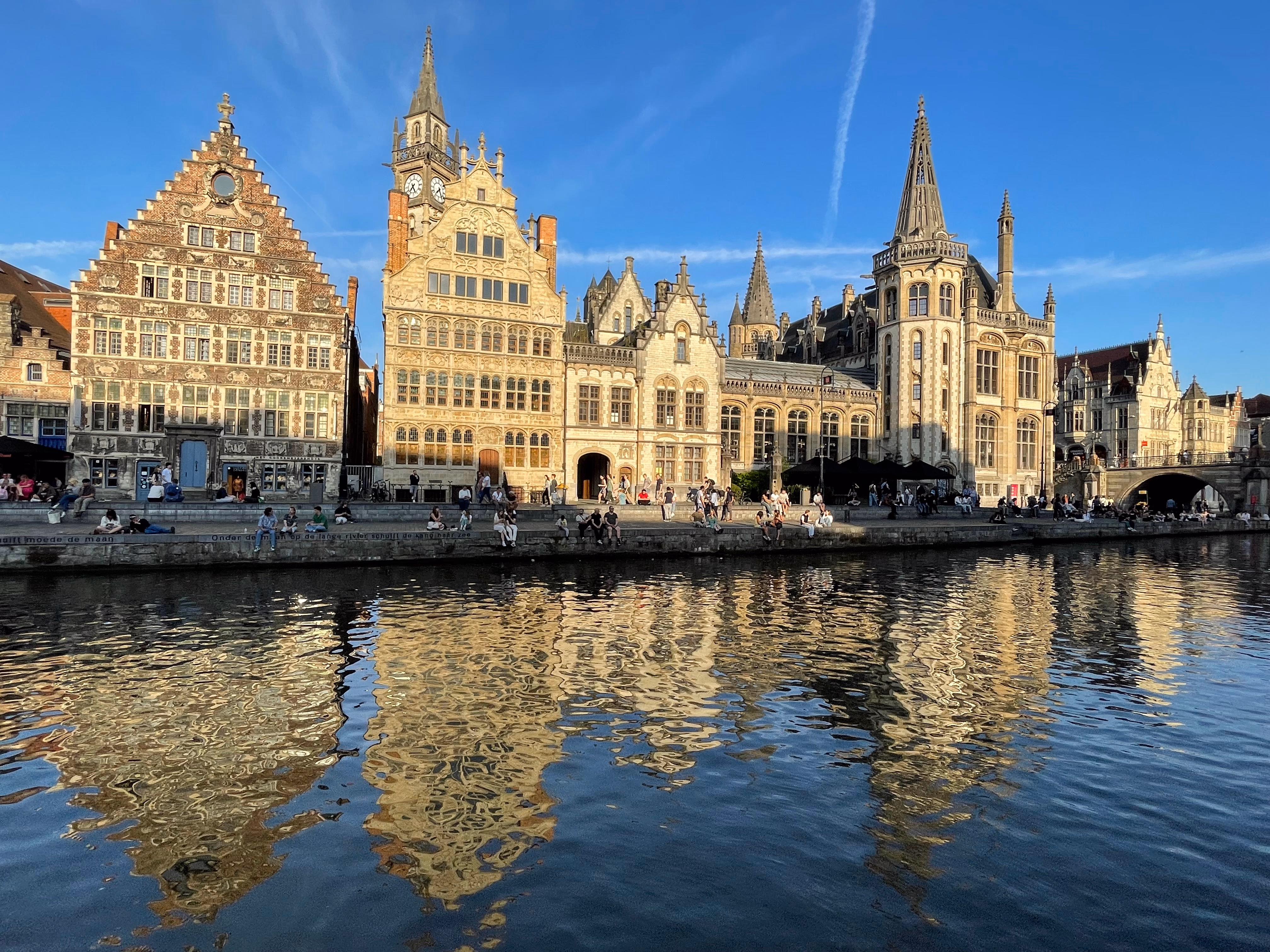 People relaxing on the banks of the Leie river in Ghent.