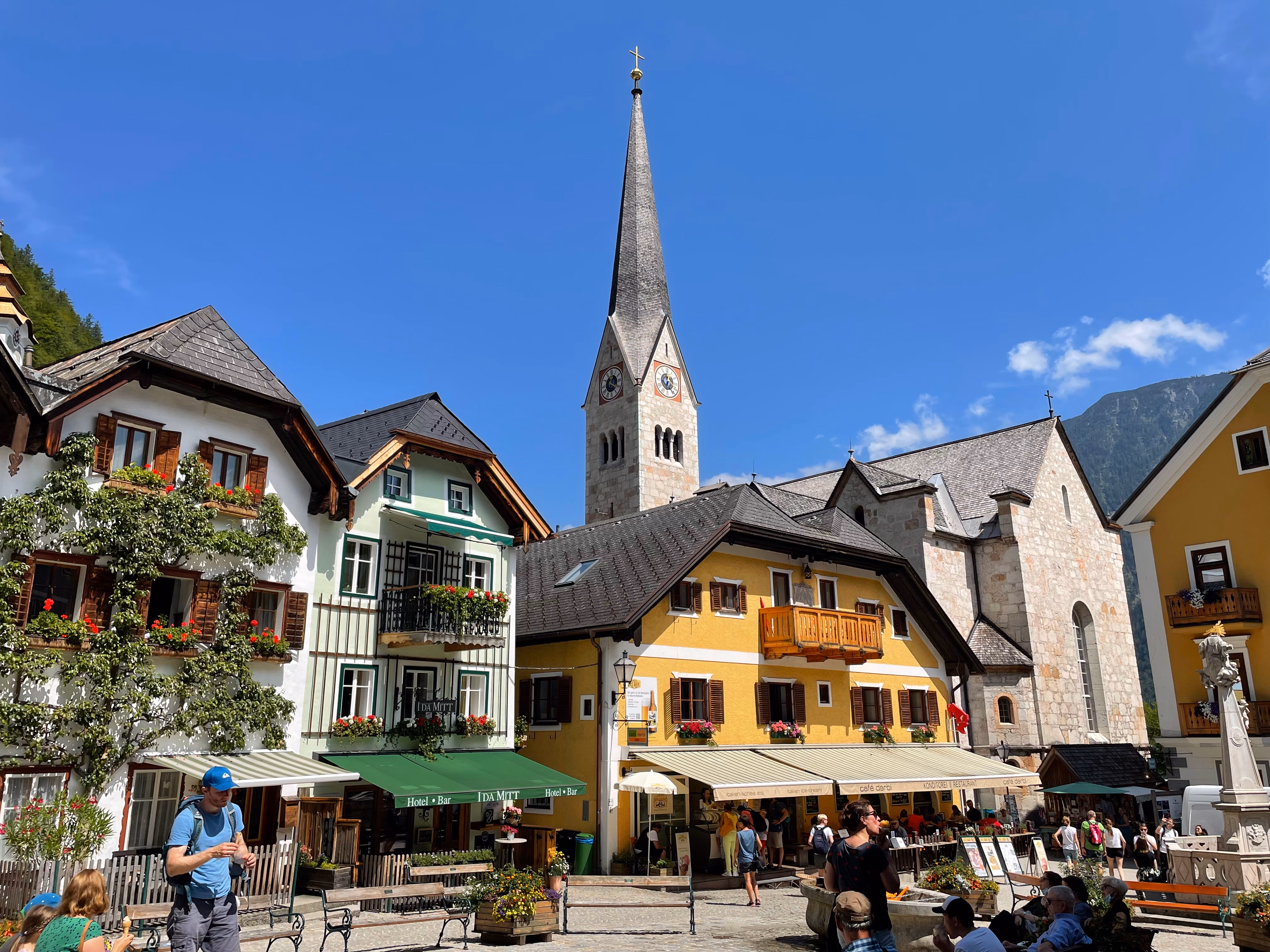 Church bell rising high from behind colorful houses in a village market square