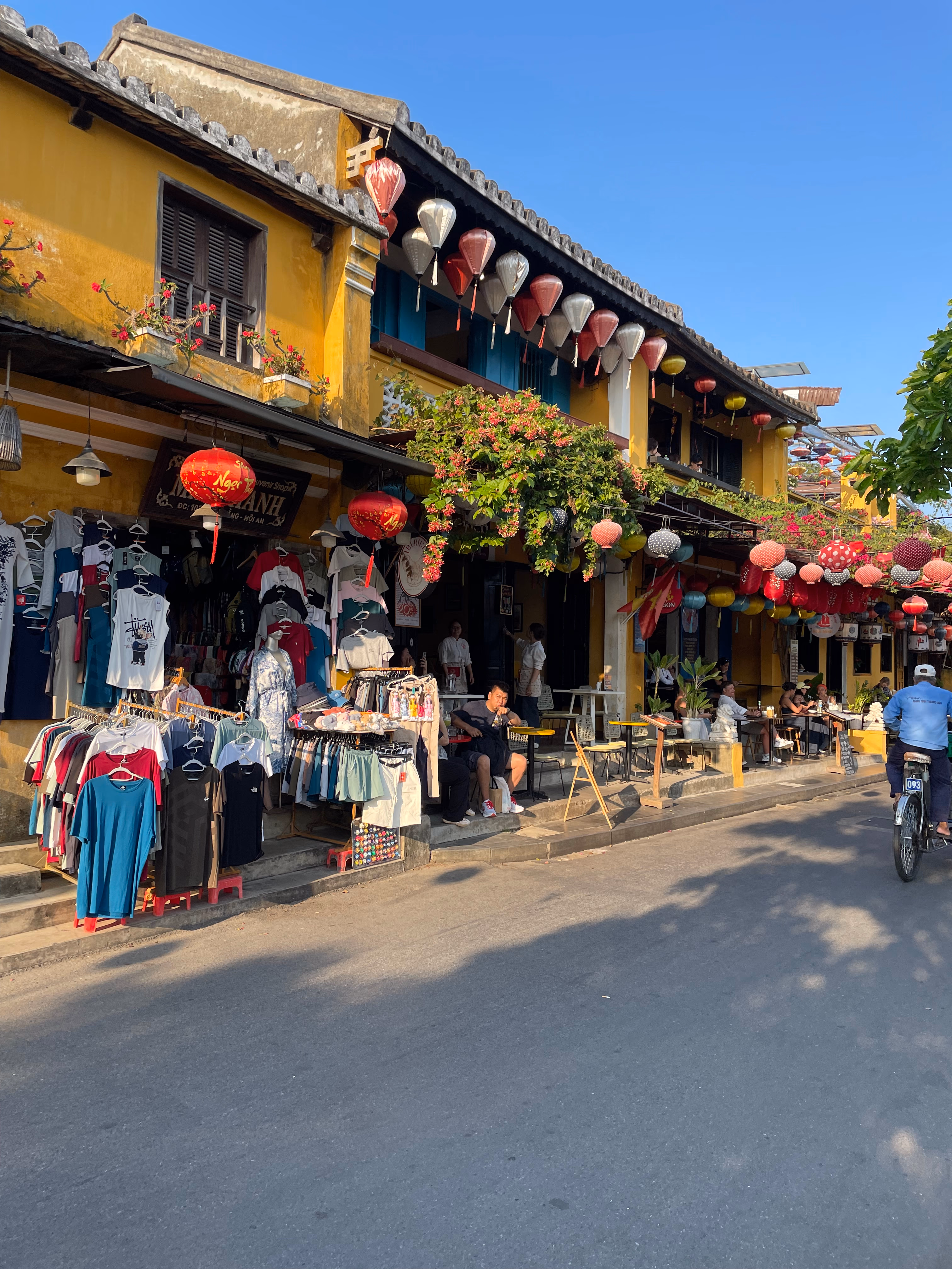 A cyclist riding through a yellow-walled street in Hoi An.