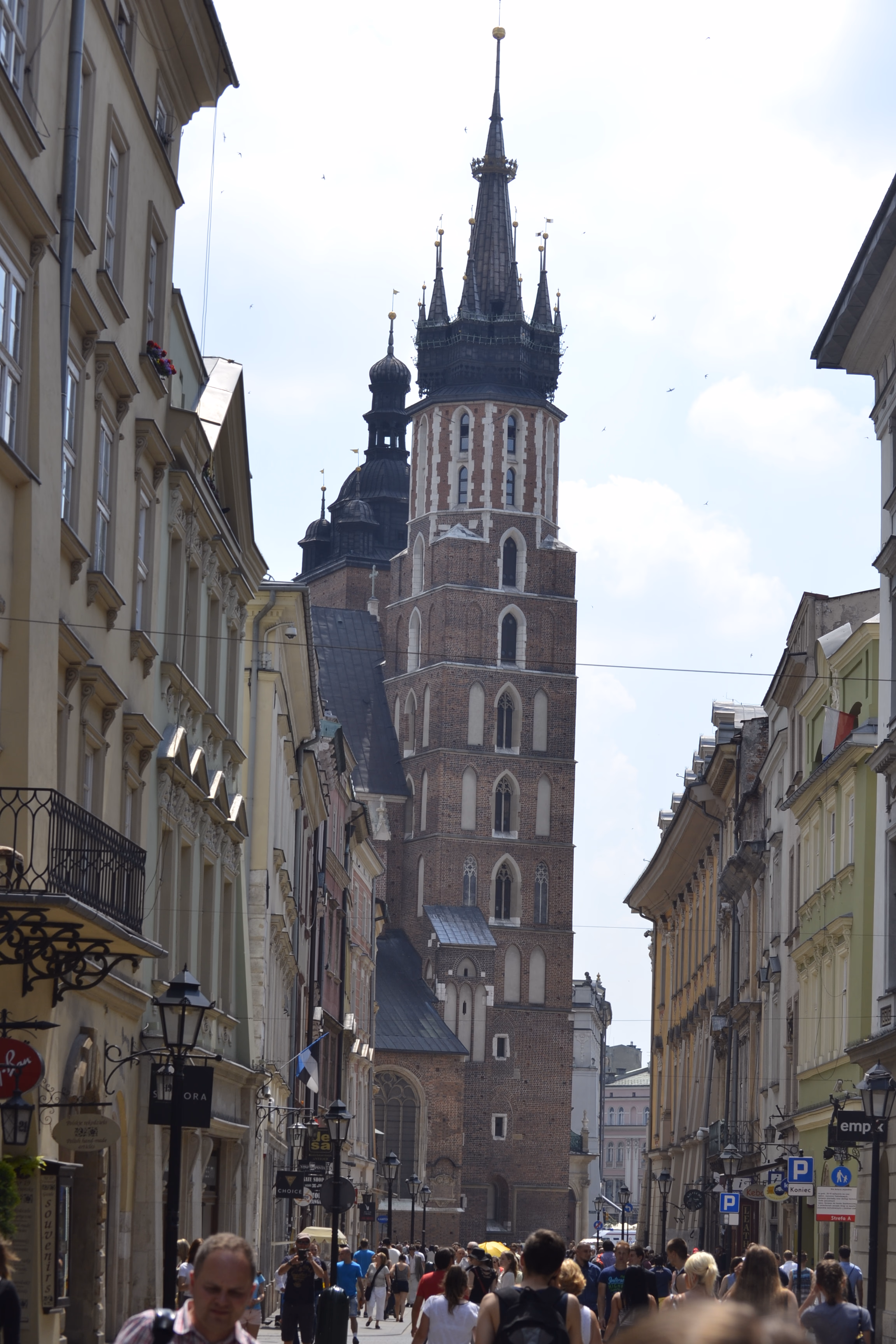 St Mary's Basilica at the end of Floriańska Street — twin brick towers and a forest of Gothic pinnacles above the old-town facades.