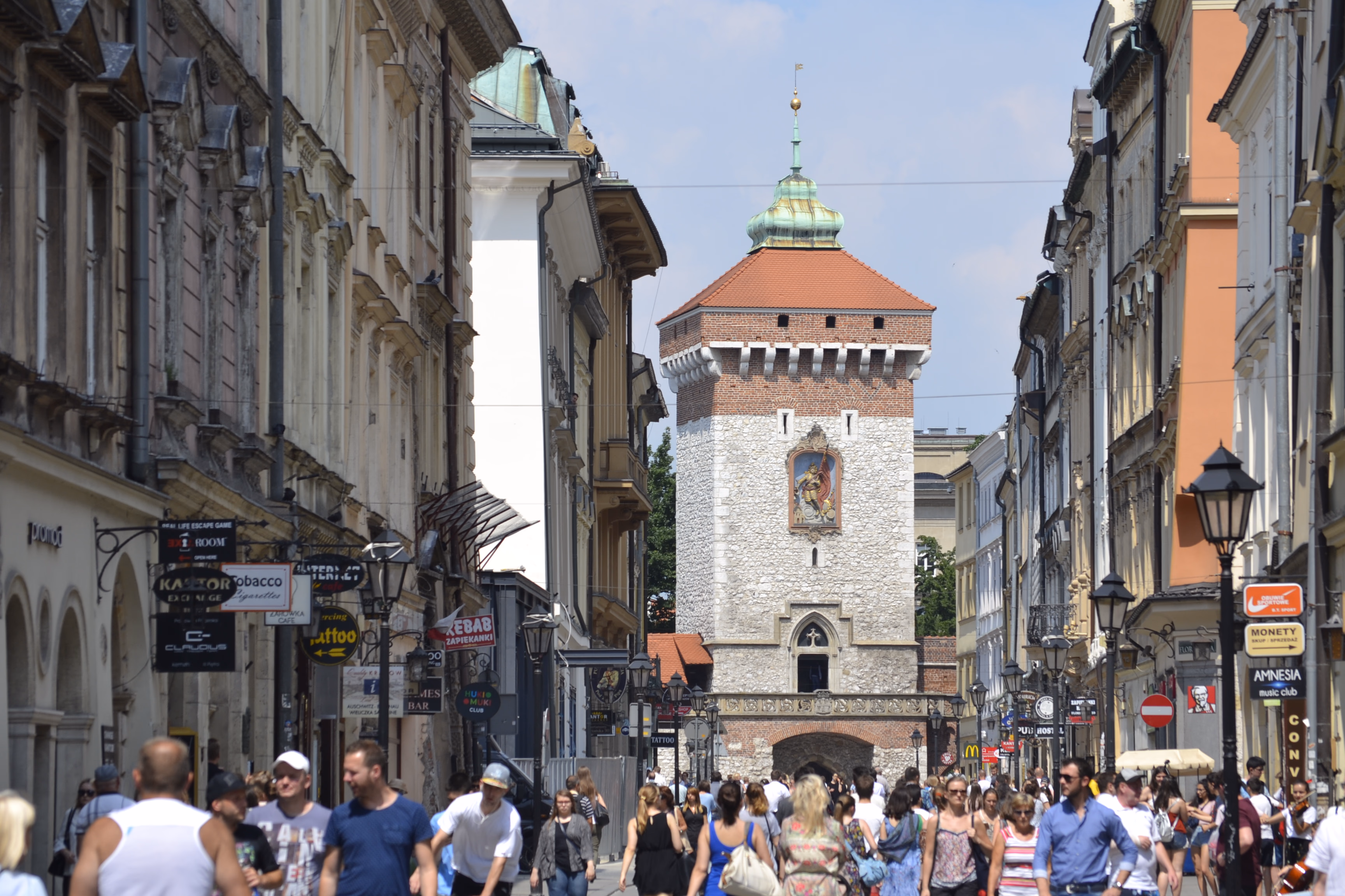 St Florian's Gate — a red-tiled roof and green spire closing the view down a lane of painted townhouses and wrought-iron signs.