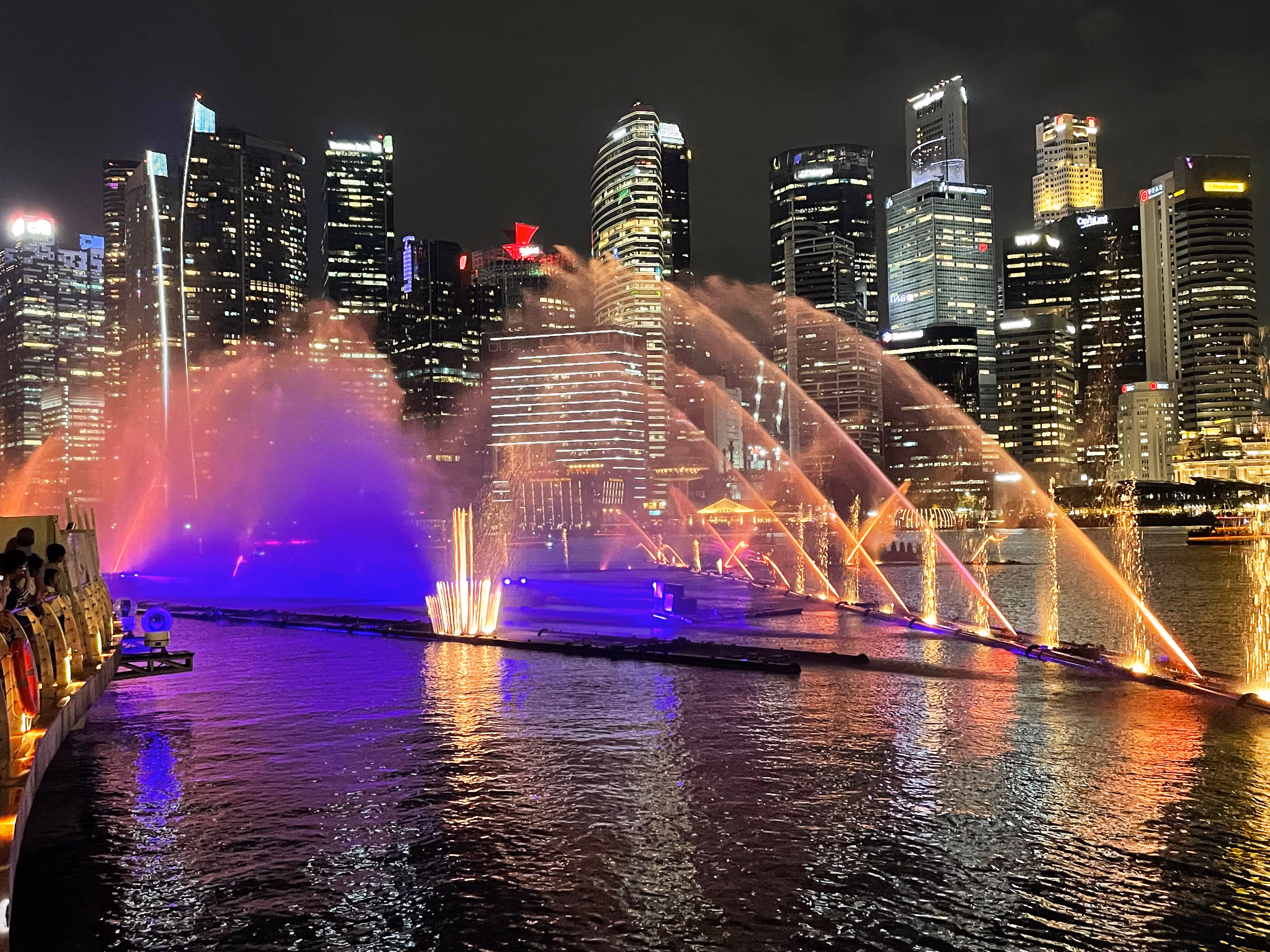 Spectra on the bay โ a fan of yellow and teal projected onto a wall of mist, water jets and light beams in front of the CBD.