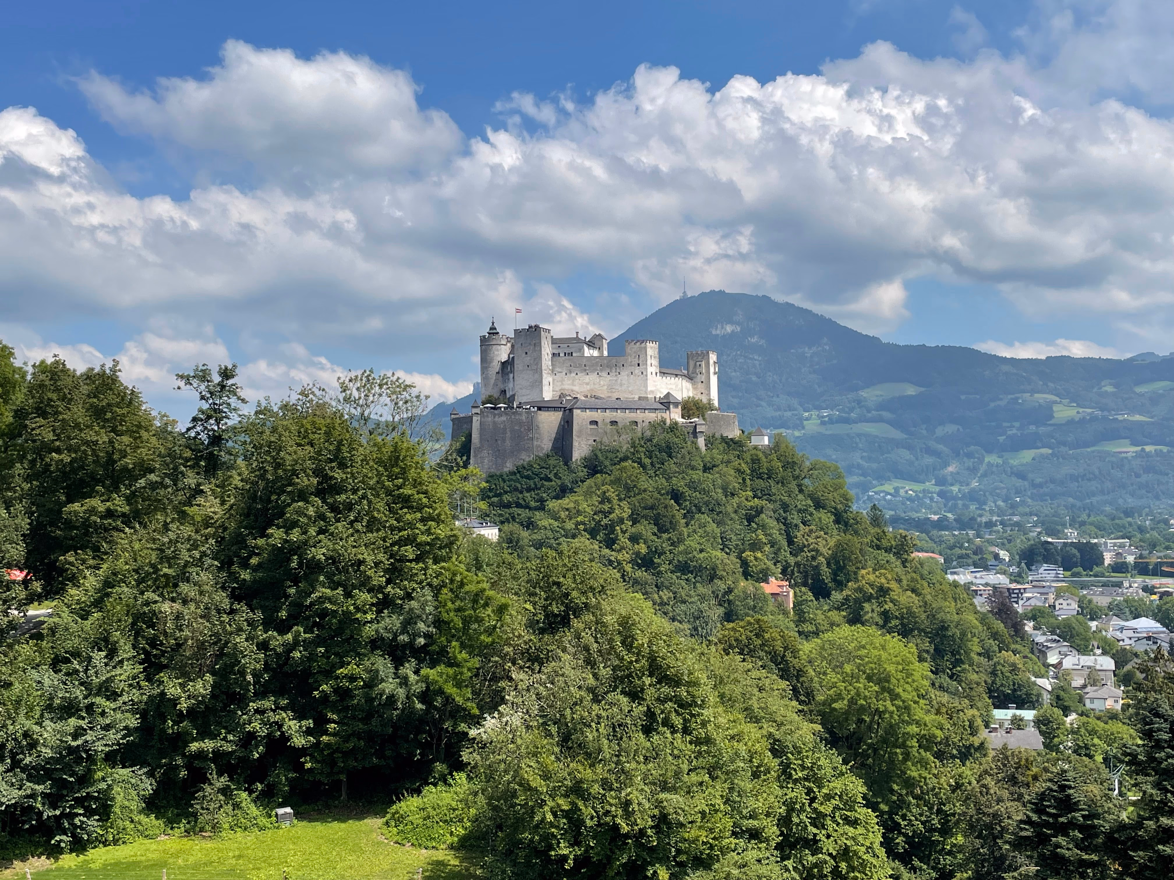 Salzburg castle on a hill with green hills in the background
